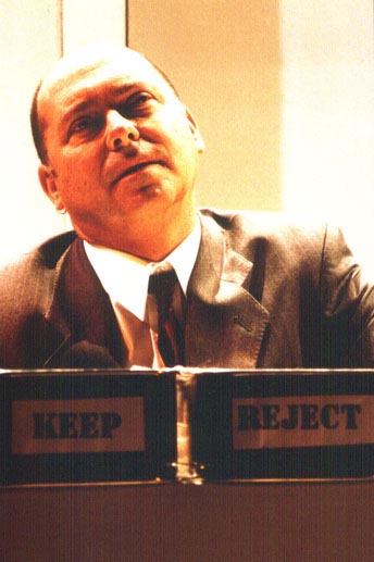 Publicity photo for Mendel. This is a close-up photo of  Garry Robson as Mendel seated at a table with two boxes in front of him - one marked Keep and the other Reject. Photo 